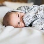 Säugling lacht im Babybett