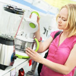Frau schaut nach verschiedenen Mixern und Food Processoren