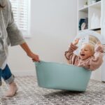 Mutter zieht Kind im Wäschekorb hinter sich her